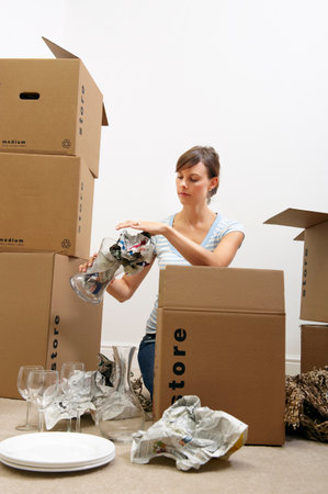 Woman packing glasses/plates in boxesの写真素材