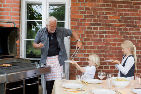 grandfather barbecuing for childrenの写真素材