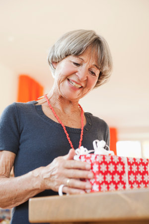 Old woman inspecting christmas presentの写真素材