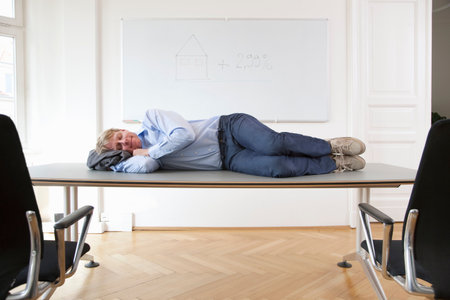 Businessman sleeping on conference tableの写真素材
