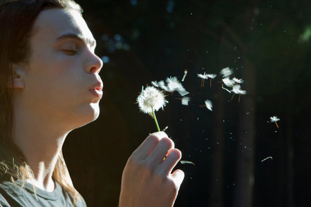 Man blowing dandelion in forestの写真素材
