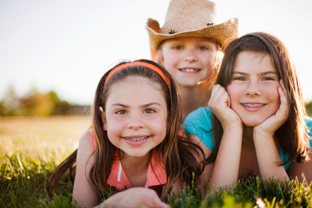 3 young girls laying in grassの写真素材