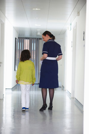 Nurse and young girl walking in corridorの写真素材