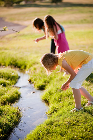 3 young girls looking in creekの写真素材
