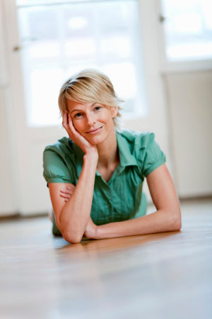 Young woman at home lying on floorの写真素材