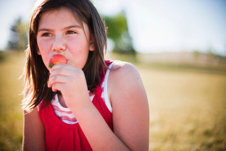 Young girl eating strawberryの写真素材
