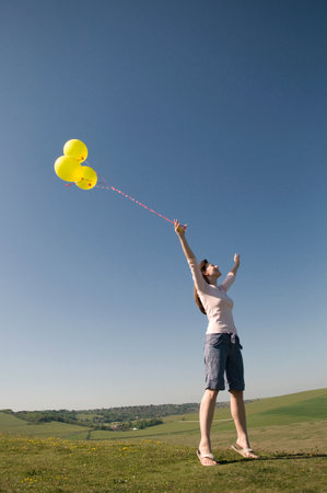 Happy woman on hill with balloonsの写真素材