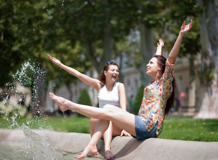 Young women splashing in a fountainの写真素材