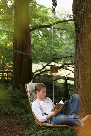 Young man reading in hammockの写真素材