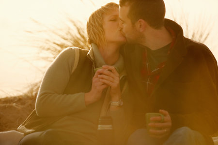 Couple outdoors kissing. With coffeeの写真素材