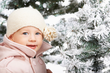 Baby girl beside snowy treesの写真素材