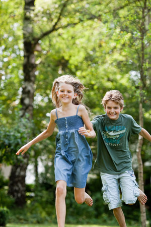 Boy chasing girl in gardenの写真素材