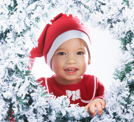 Baby girl looking through the snowy treeの写真素材