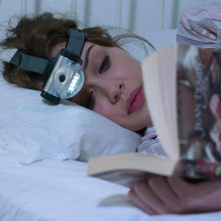 Young woman reading with head torchの写真素材