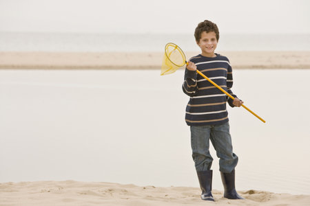 Young boy at beach holding fishing netの写真素材