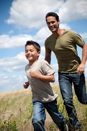 Father and son running through a fieldの写真素材