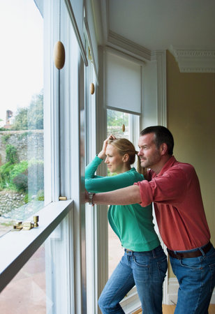 Couple standing by window togetherの写真素材