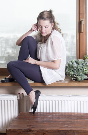 Woman talking on phone at windowsillの写真素材