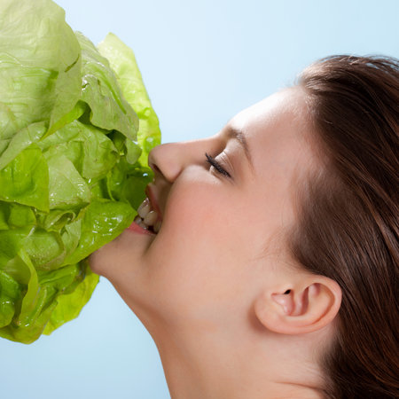Woman eating a head of lettuceの写真素材