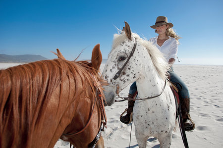 2 people riding horses on the beachの写真素材