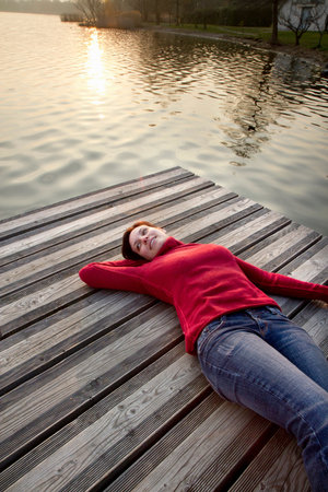 Woman laying on jetty over lakeの写真素材