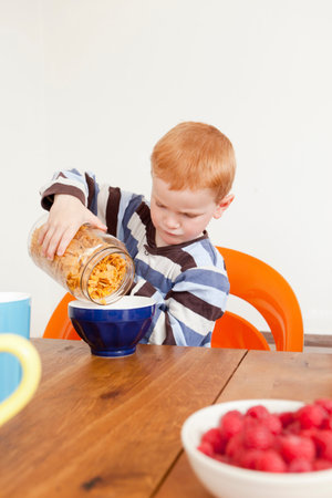 Boy pouring himself bowl of cereal