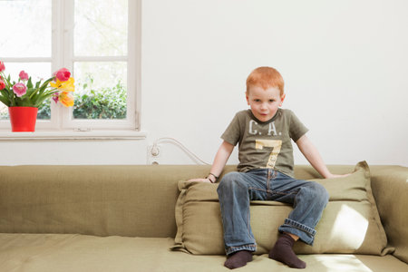 Boy sitting on sofa cushionの写真素材