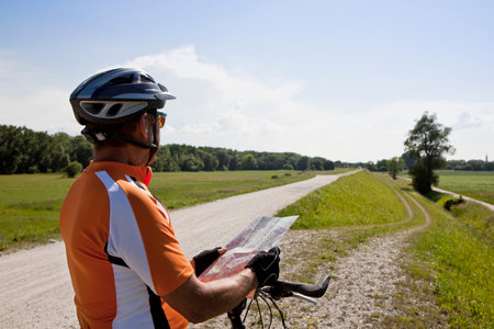 Biker reading map on rural roadの写真素材