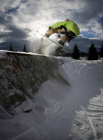 Snowboarder jumping on half-pipe