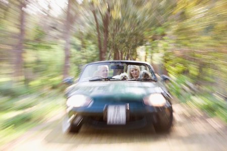 Blurred view of convertible on dirt pathの写真素材