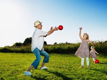 Father playing with daughters outdoorsの写真素材