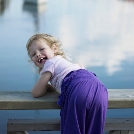 Girl leaning over railing of pierの写真素材