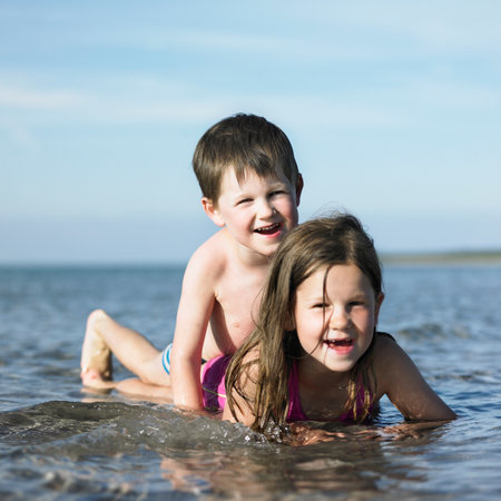 Children playing in waves on beachの写真素材