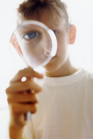 Boy peering through magnifying glassの写真素材