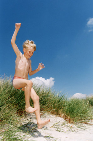Boy in swimsuit playing on beachの写真素材