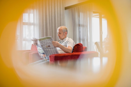 Man reading newspaper in armchairの写真素材