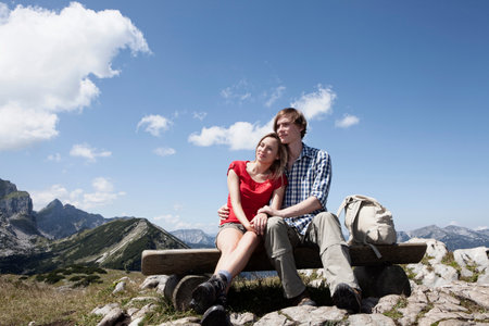 Couple sitting on bench on hilltopの写真素材