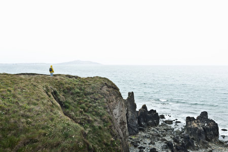 Hiker overlooking ocean from cliffの写真素材