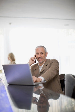 Businessman on phone using laptopの写真素材