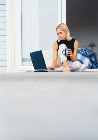 Woman using laptop on porchの写真素材
