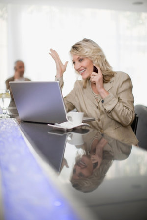 Businesswoman on phone using laptopの写真素材