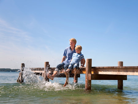 Father and son dangling feet in lakeの写真素材