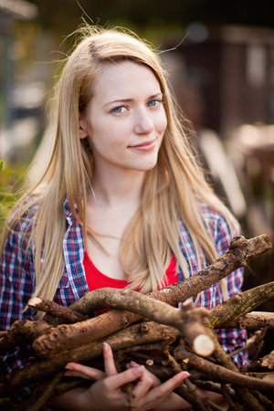 Woman gathering firewood in gardenの写真素材