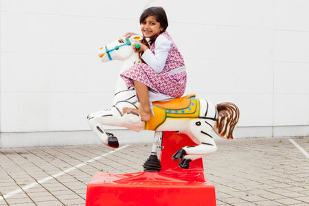 Girl riding mechanical horse outdoorsの写真素材