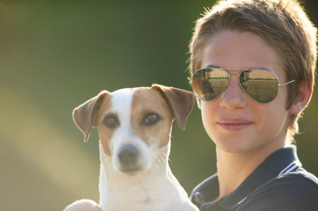 Teenage boy holding dog outdoorsの写真素材