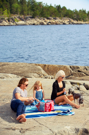 Family having picnic on rocks by lakeの写真素材