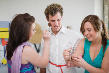 Teenage girls putting makeup on boyの写真素材