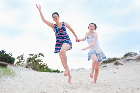 Woman and girl running on beachの写真素材