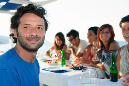 Man smiling at table with friendsの写真素材