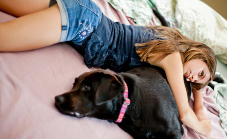 Girl relaxing with dog on bedの写真素材